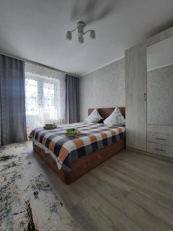 a bedroom with a bed and a large window at 2-х комнатная Квартира in Uralsk