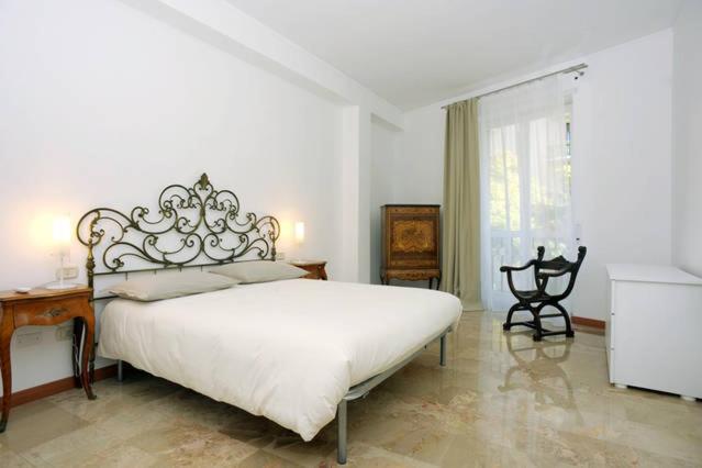 a white bedroom with a large bed and a window at Castedd'House in Cagliari