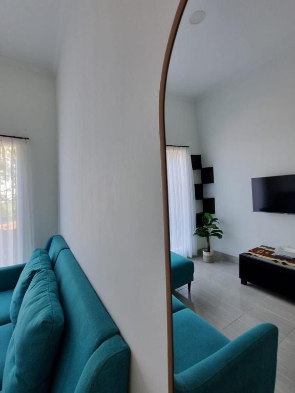 a living room with a blue couch and a mirror at Asaan homestay in Ciburial
