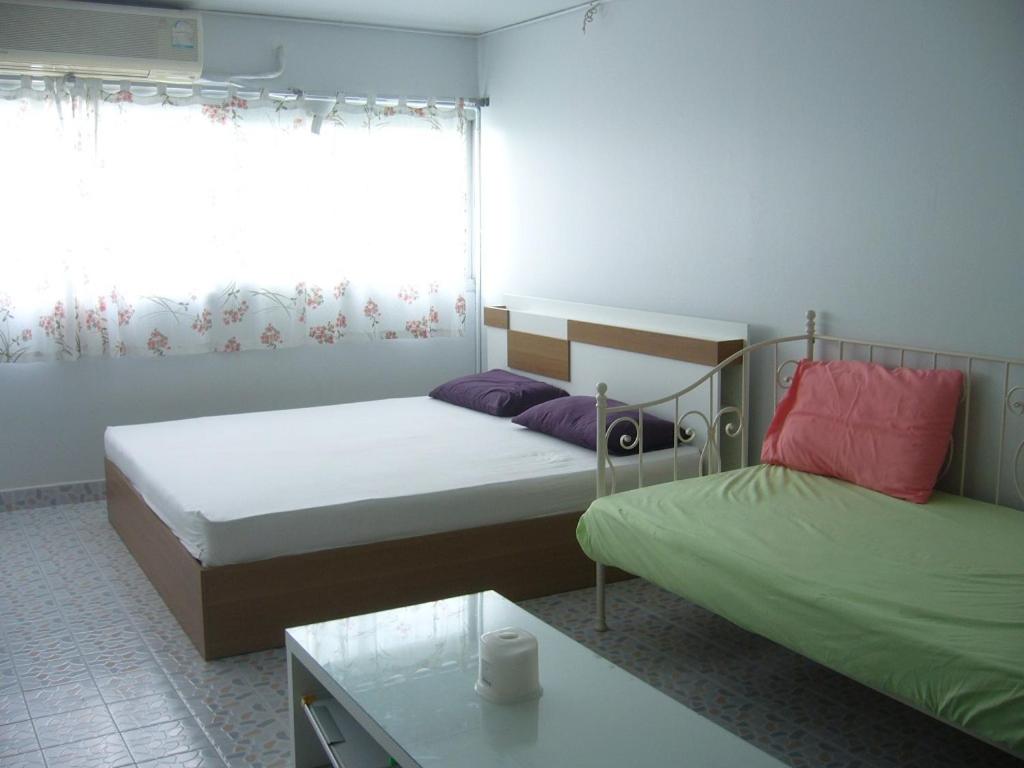 a bedroom with two beds and a table and a window at T8 Guest House Don Mueang Challenger in Bangkok