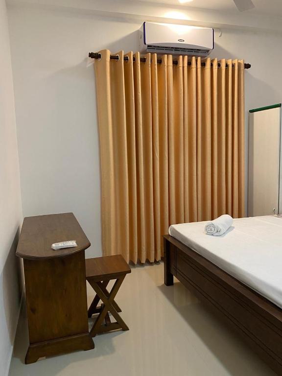 a bedroom with a bed and a table and a curtain at Labuduwa Rest in Galle