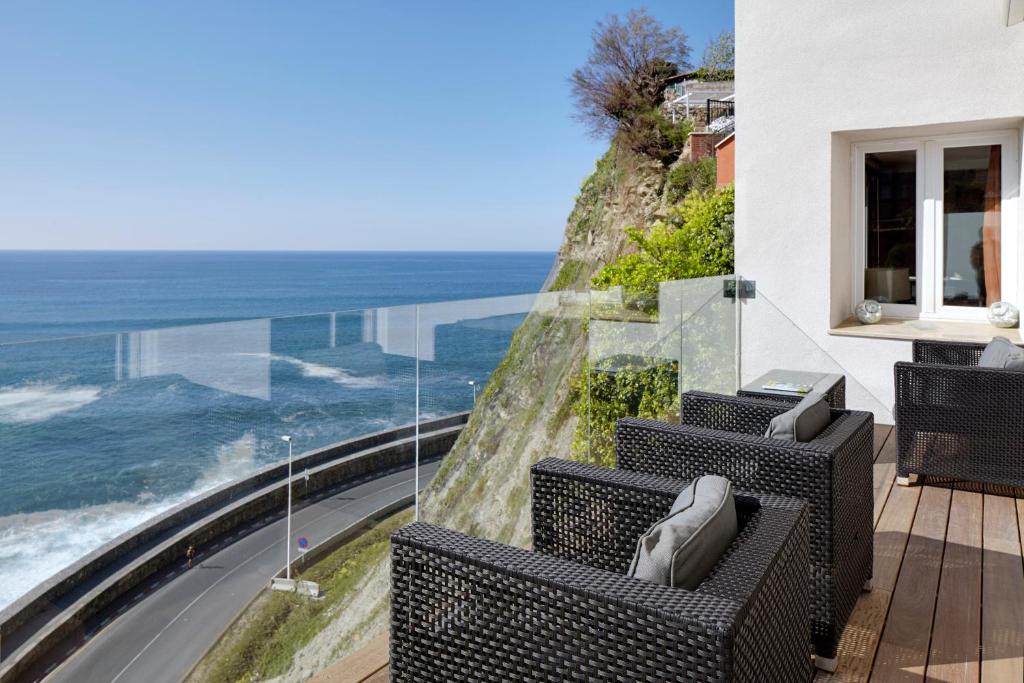 Un balcón con sillas y vistas al océano. en Saiaz Getaria Hotela, en Getaria
