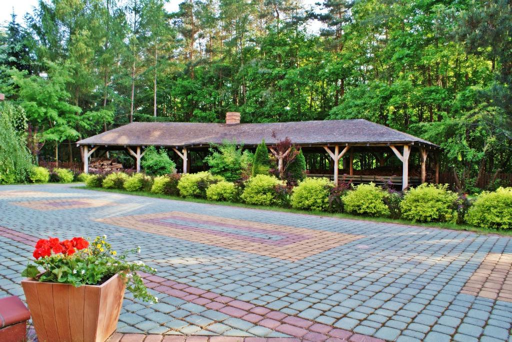 Outdoor pavilion surrounded by lush greenery and paved courtyard.