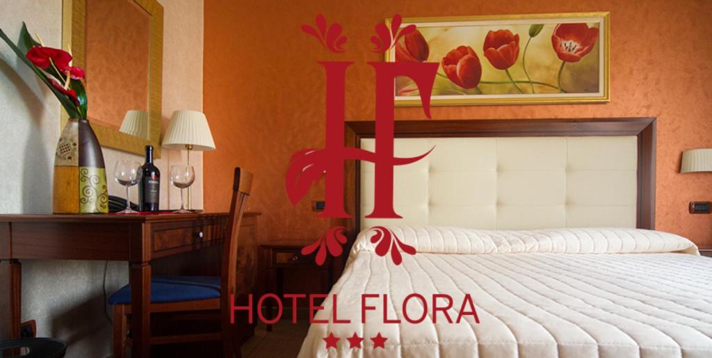 una camera con letto, tavolo e scrivania di Hotel Flora a Noto