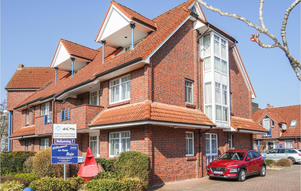 a red brick house with a car parked in front of it at Ferienwohnung Himmelsglueck in Wangerland