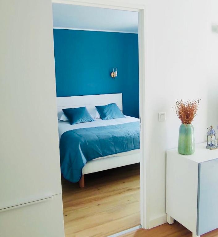 une chambre avec un lit avec un mur bleu dans l'établissement Quartier de la plage, à Roquebrune-Cap-Martin