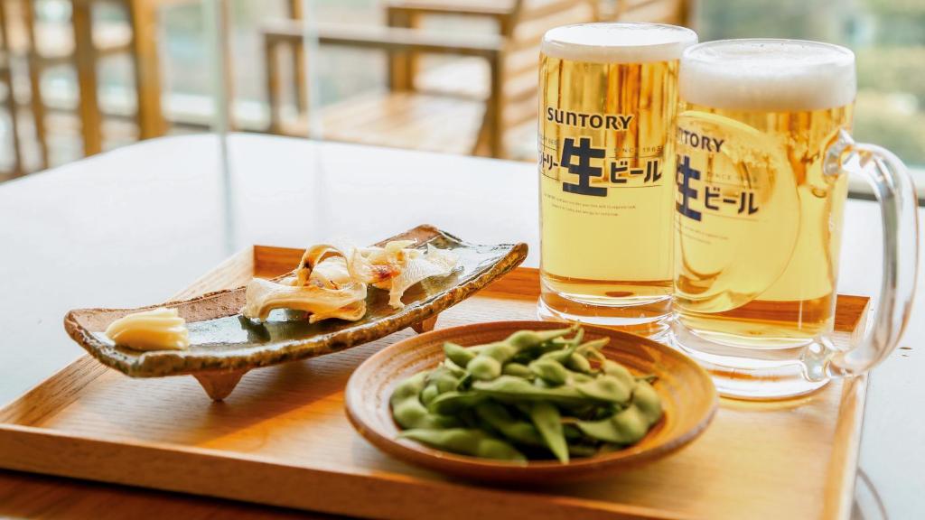 a tray with a plate of food and two glasses of beer at 熱海山荘 in Atami