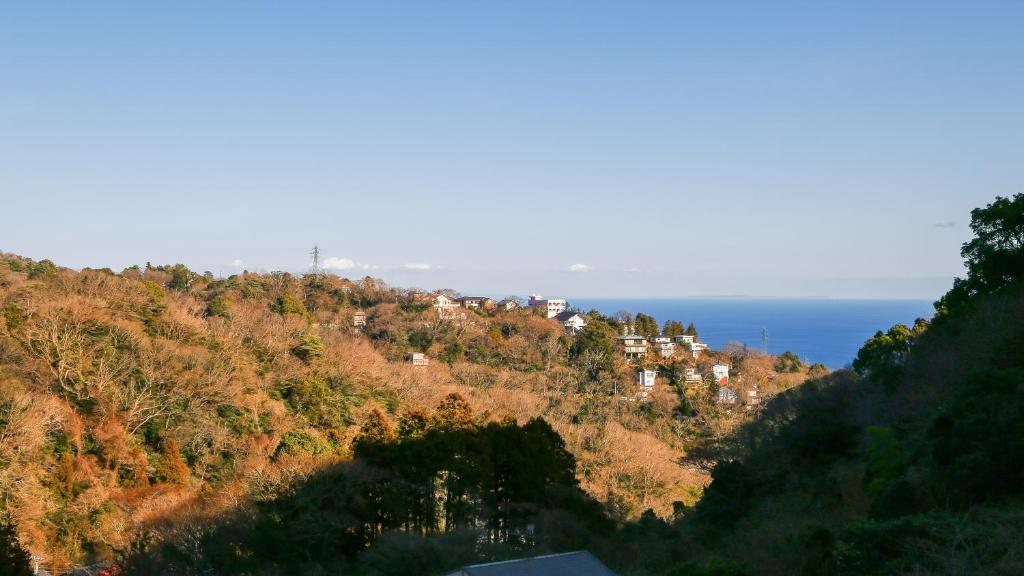 a town on a hill with the ocean in the background at 熱海山荘 in Atami