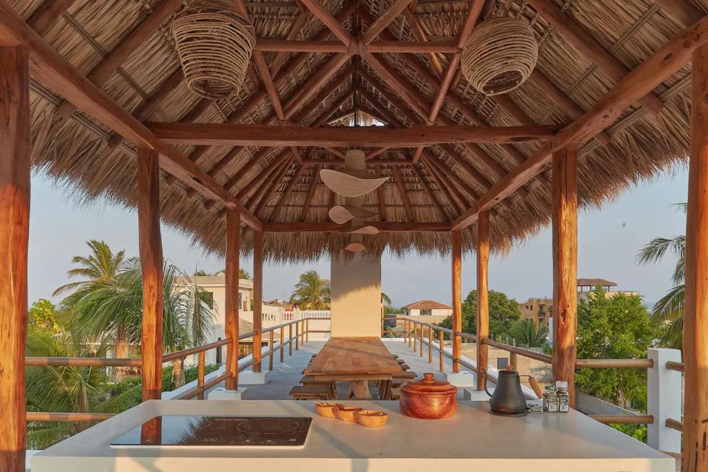 a large wooden pavilion with a table on a beach at Casa Ohma La Punta in Brisas de Zicatela