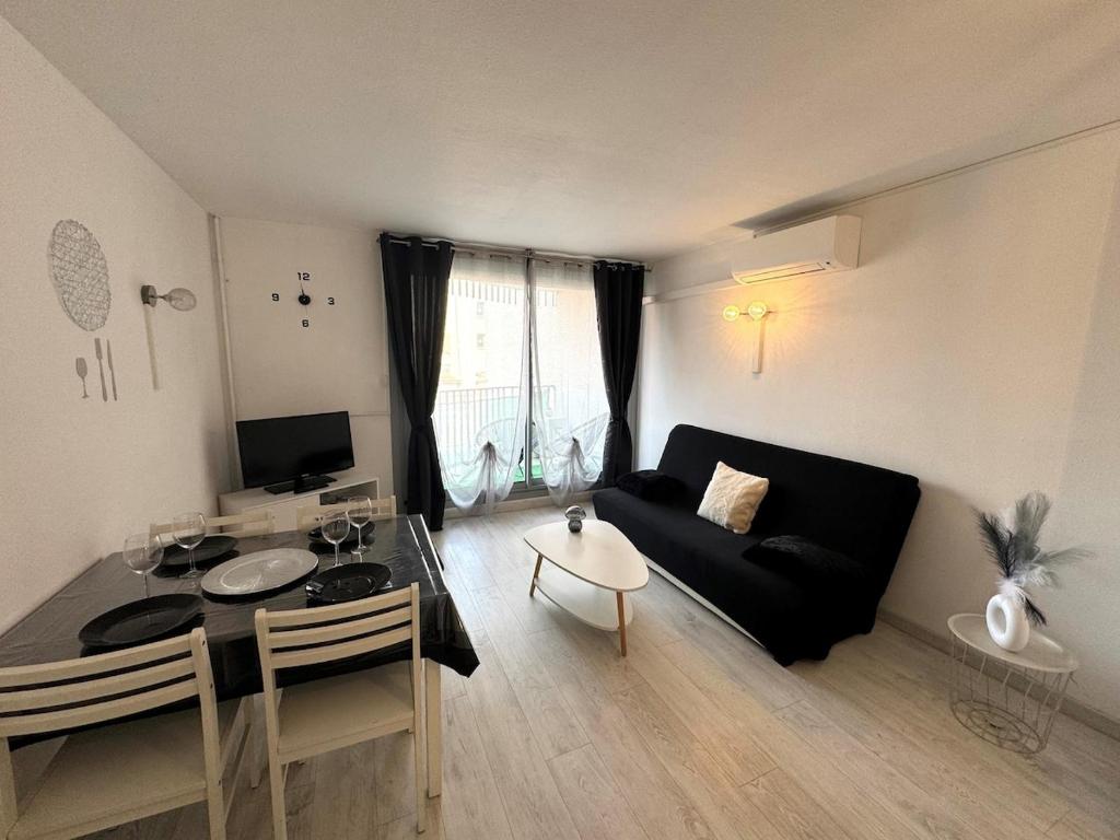 un salon avec un canapé noir et une table dans l'établissement Appartement - Cap d'Agde, au Cap d'Agde