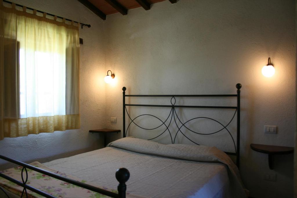 Ce lit se trouve dans une chambre dotée de 2 lampes et d'une fenêtre. dans l'établissement Borgo Antico, à Poggioni