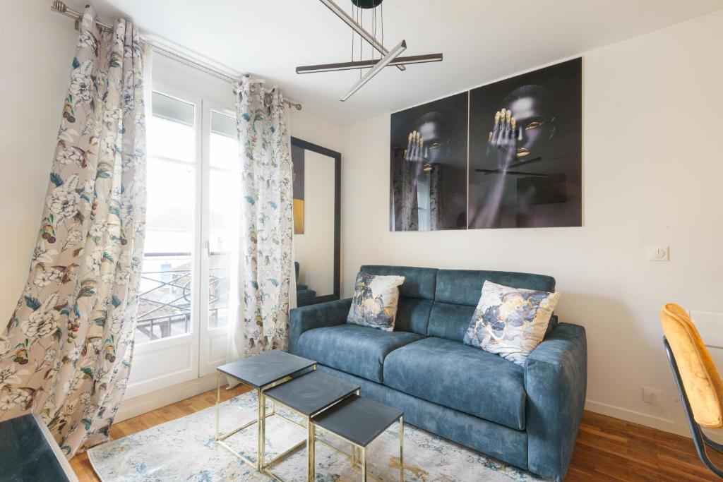 un salon avec un canapé bleu et une fenêtre dans l'établissement Aux Berges de Bailly - A 10min de Disneyland, à Bailly-Romainvilliers