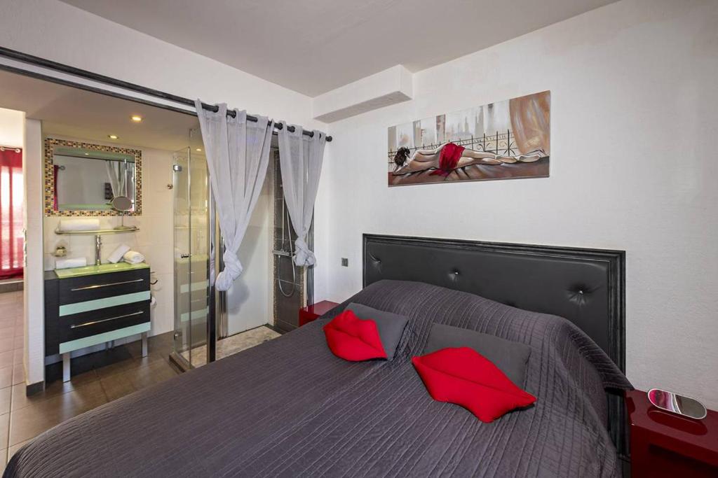 - une chambre avec un lit doté d'oreillers rouges dans l'établissement Appartement POMME D'AMOUR Port Nature PN423 - Luxe - 2 personnes, au Cap d'Agde