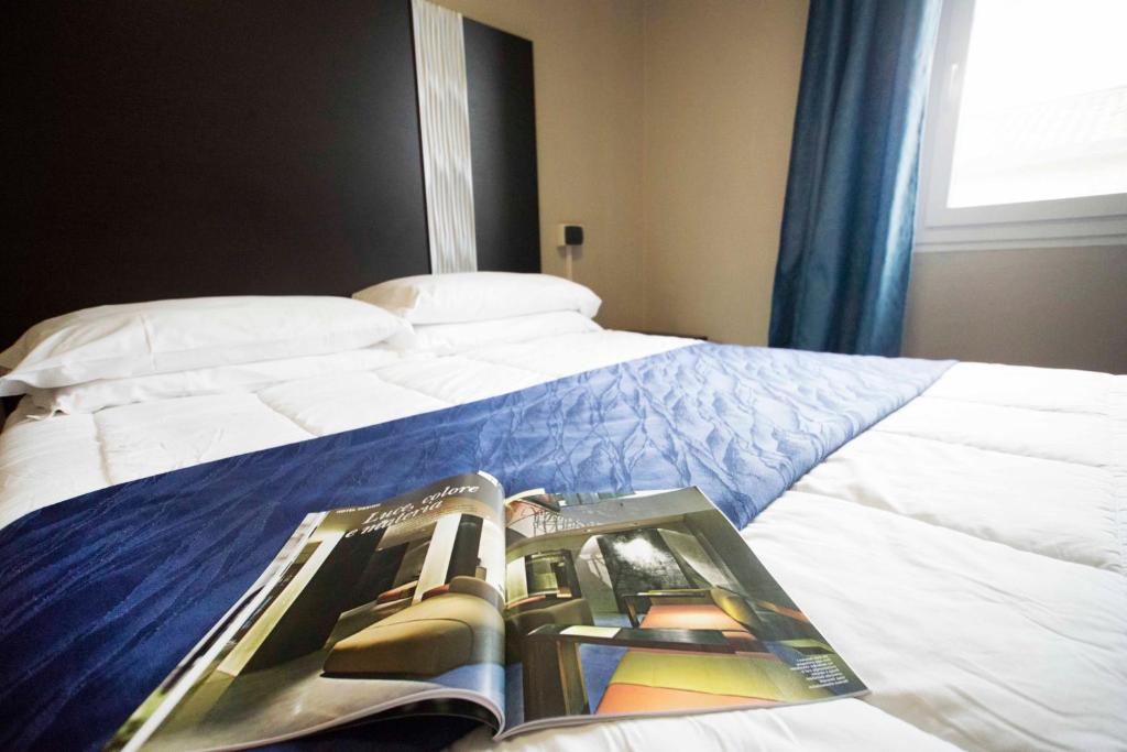 a bedroom with a bed with a book on it at Hotel Principe in Casale Monferrato
