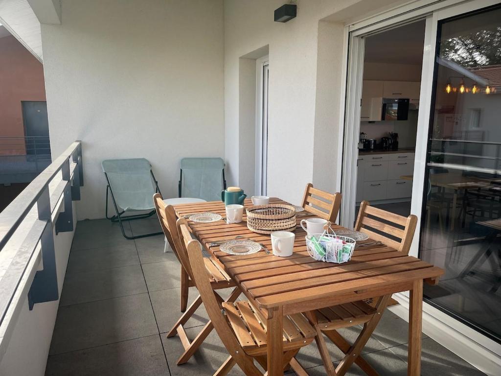 une table et des chaises en bois sur un balcon dans l'établissement Appartement lumineux 5 personnes, à La Teste-de-Buch