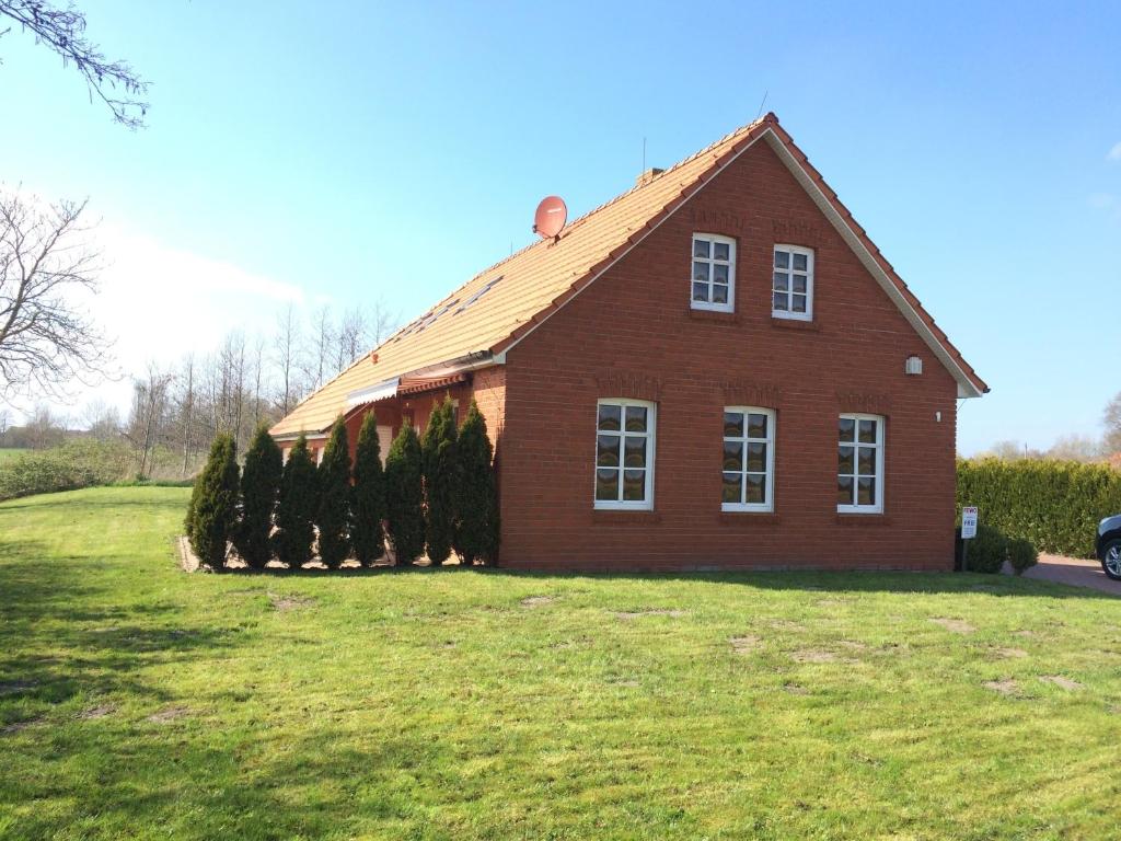 a red brick house with trees in front of it at Lütje Huus in Norden
