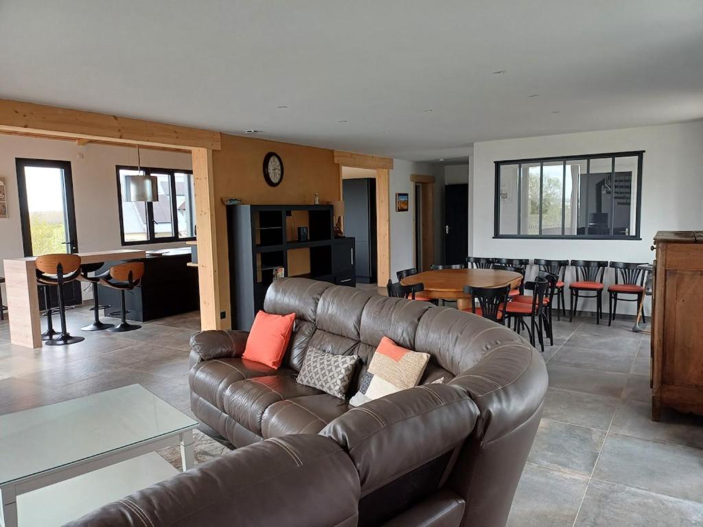 a living room with a leather couch and a table at Au bon coin de la baie in Vains