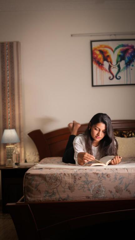 a woman laying on a bed reading a book at Luho Ever shine in Bangalore