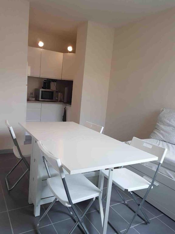 - une table et des chaises blanches dans une chambre avec cuisine dans l'établissement Studio les pieds dans l'eau, au Grau-du-Roi