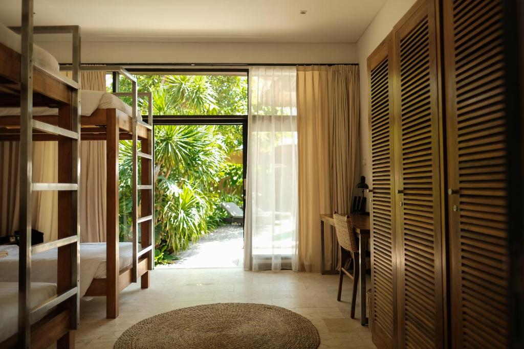 una camera da letto con letti a castello e una porta con una scrivania di Wave House Resort Canggu a Canggu