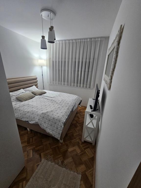 a small bedroom with a bed and a window at ZARA Apartman Živinice in Živinice