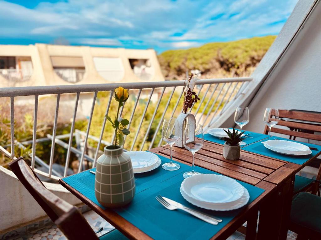 une table avec des assiettes et des verres à vin sur un balcon dans l'établissement Rivage de March Land - Parking Gratuit, à La Grande Motte