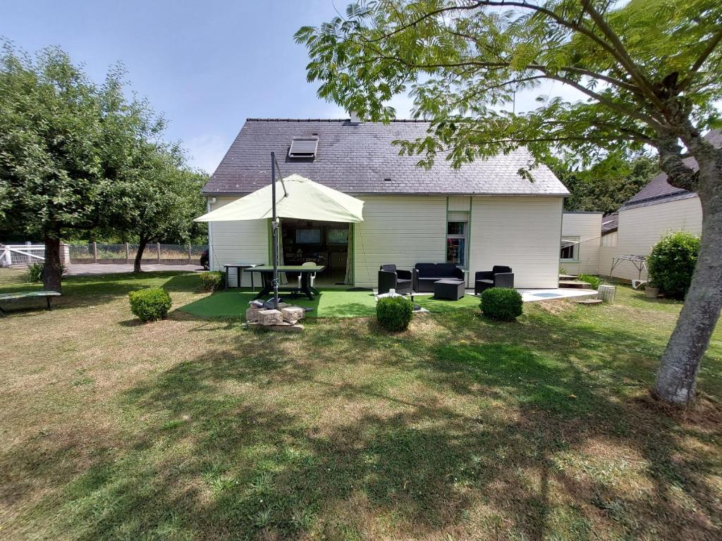 une maison avec un patio avec une table et des chaises dans l'établissement L' Albizia, à Sarzeau