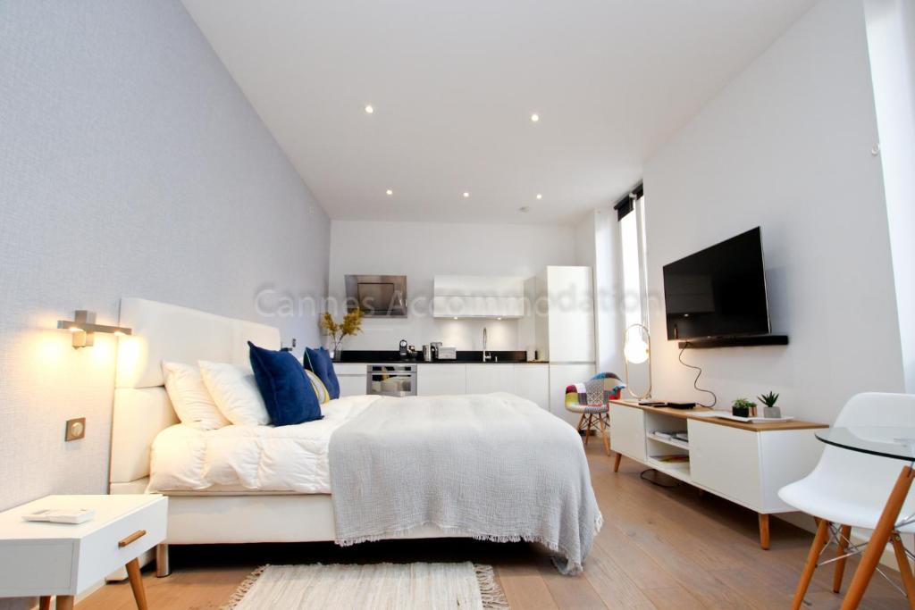 une chambre blanche avec un lit et une télévision dans l'établissement Pampelonne, à Cannes