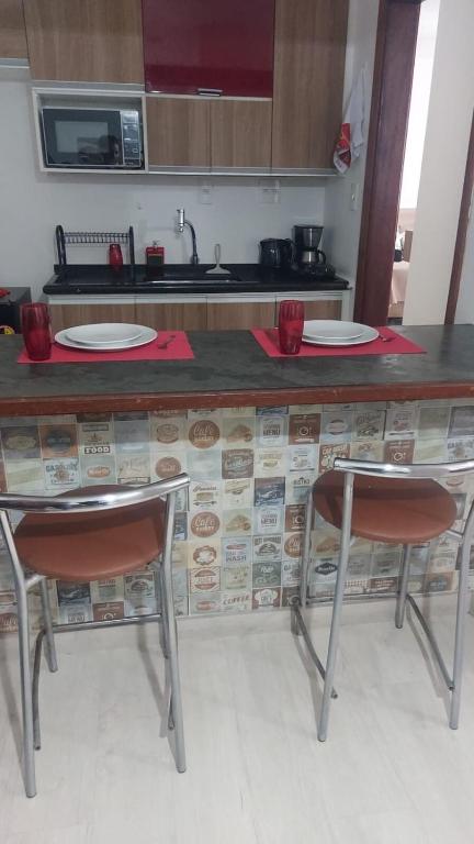 a kitchen with a counter with two chairs and a counter top at Flat próximo ao Shopping e Praia in São Vicente