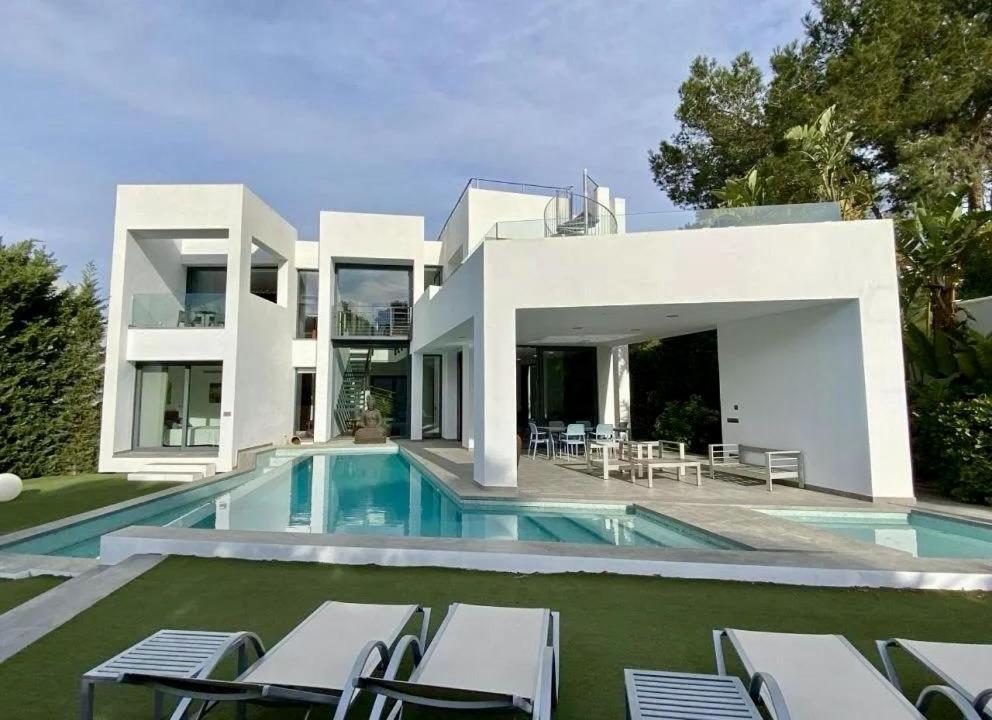 a large white house with a swimming pool at Villa Lux Mar in Cala Llena