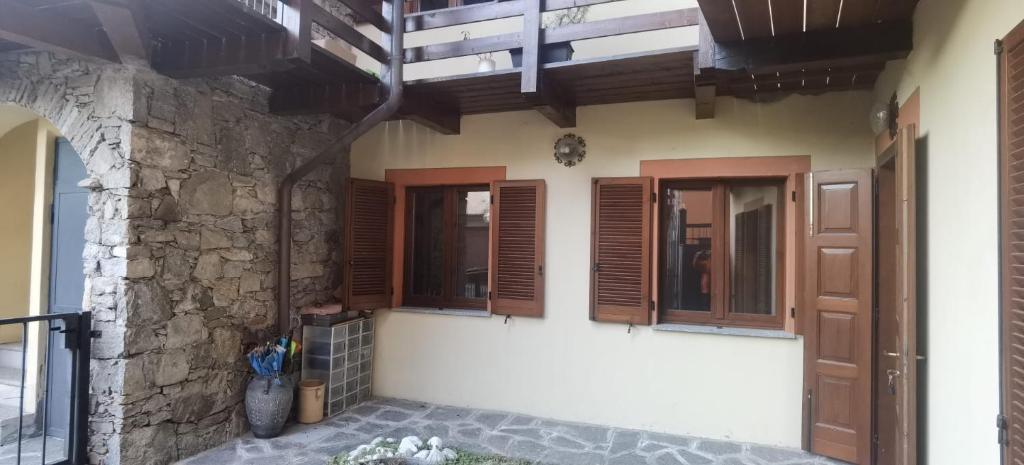 a house with wooden windows and a stone wall at Meina, 2 camere, 2 bagni, giardinetto in Meina