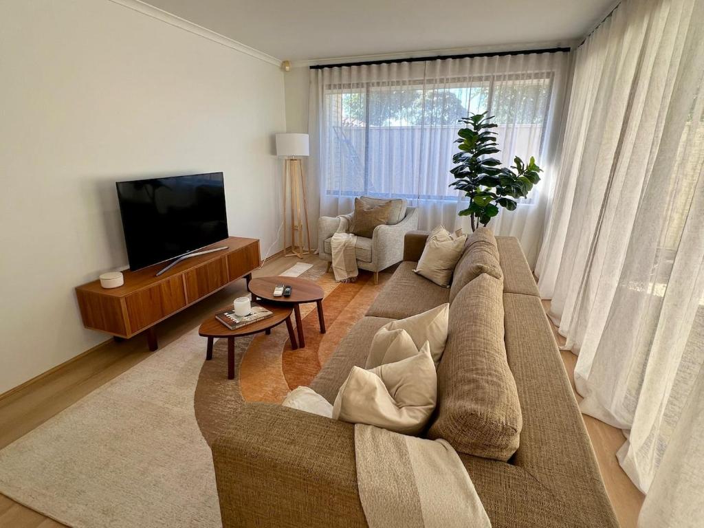 a living room with a couch and a tv at Stylish Armadale Getaway in Armadale
