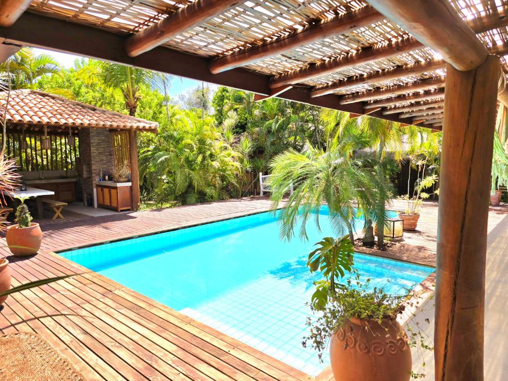 a swimming pool with a pergola and a house at Chalé Carnaval do Sol in Porto Seguro