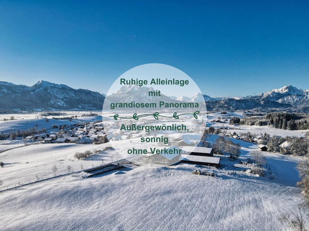 ein Schild im Schnee mit Bergen im Hintergrund in der Unterkunft Chalet - Ferienwohnungen - Biohof Stöger - Panoramasüdbalkon - grandiose Aussicht auf See, Berge und Schloss Neuschwanstein in Rieden