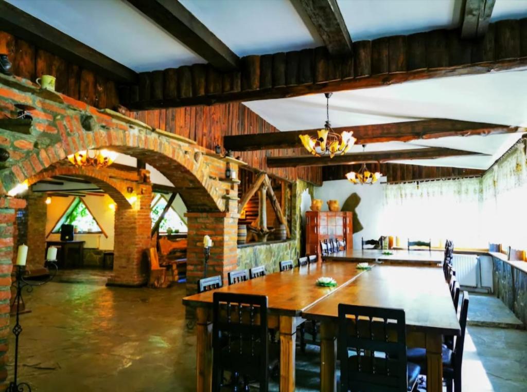 a dining room with a large wooden table and chairs at Pensiunea Cerbul - Valea Dobârlăului in Valea Dobîrlăului