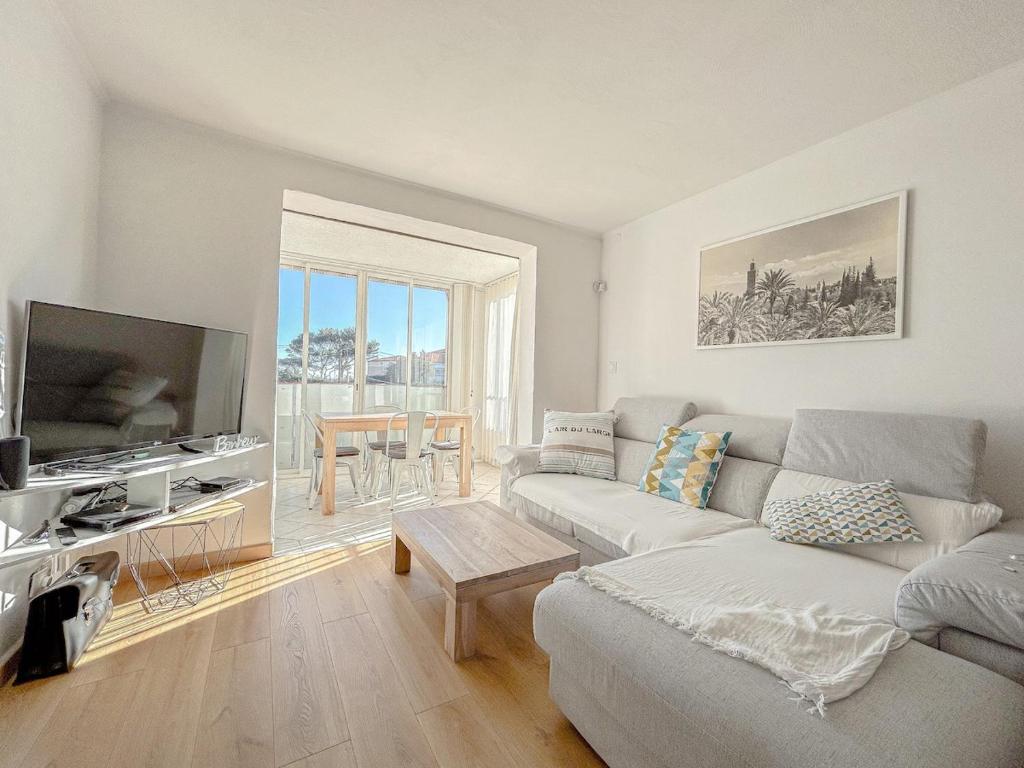 un salon avec un canapé et une télévision à écran plat dans l'établissement Vue mer et parking privé, T2 avec accès plage, à Fréjus