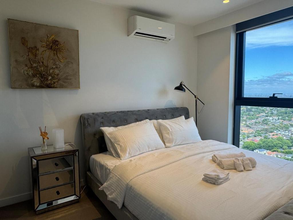 a bedroom with a large bed with a window at Box Hill luxury 29th floor apartment with car park in Box Hill