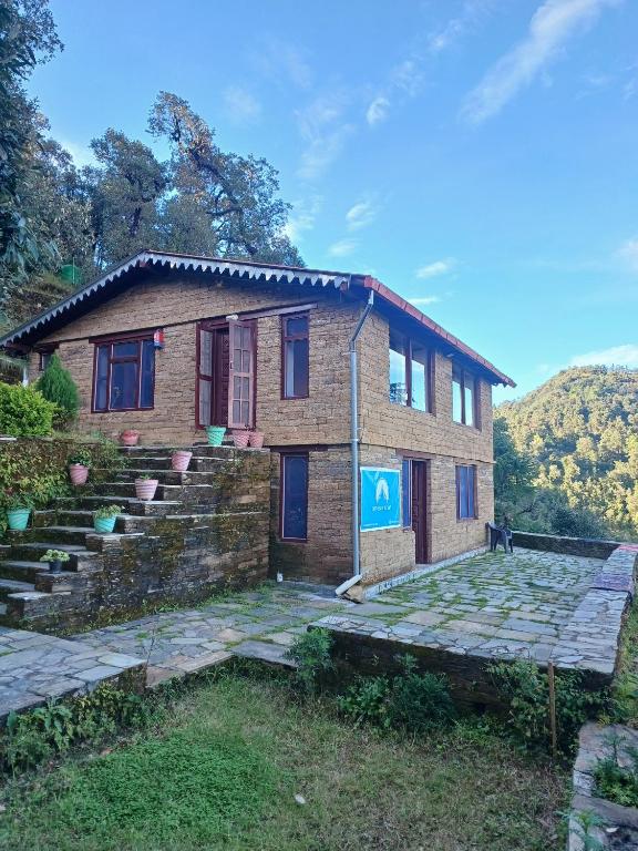 a brick house with stairs in front of it at Odyssey Stays Jageshwar Dham in Panuānaula