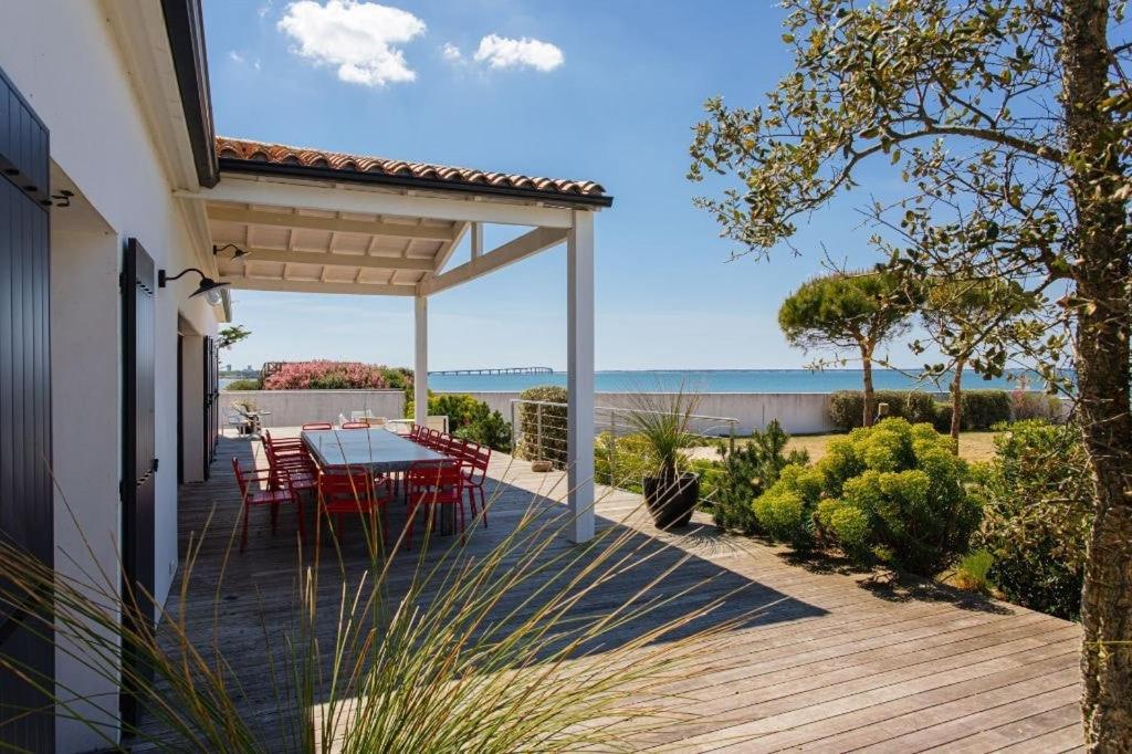 une terrasse en bois avec une table et des chaises dessus dans l'établissement Villa 180 Mer La Rochelle Ile de Ré, à LʼHoumeau