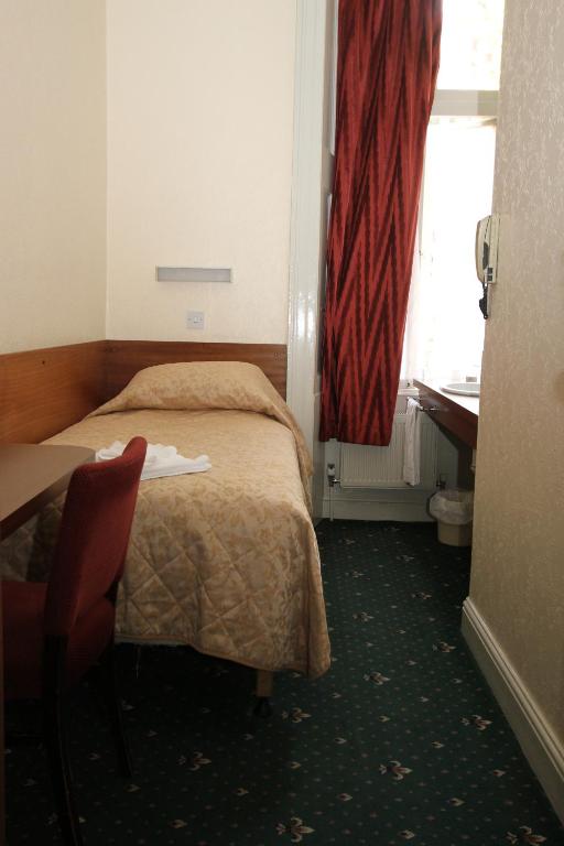 a hotel room with a bed and a desk and a window at Ridgemount Hotel in London