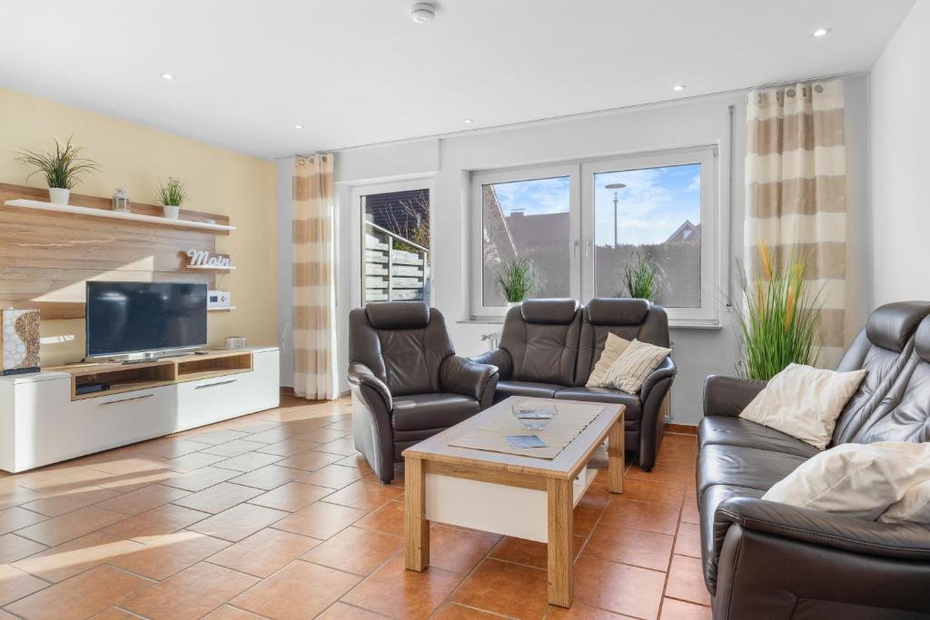 ein Wohnzimmer mit Ledermöbeln und einem Flachbild-TV in der Unterkunft Ferienhaus Kristina in Hooksiel
