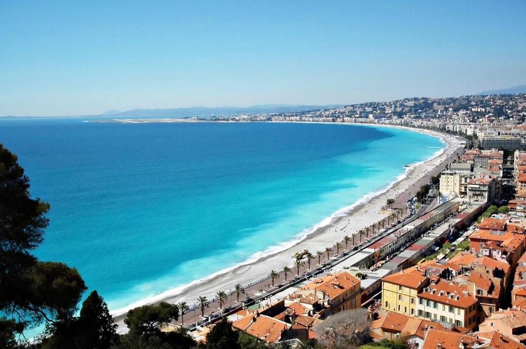 une vue d'une plage avec des bâtiments et l'océan dans l'établissement Spacieux appartement climatisé centre Nice, à Nice