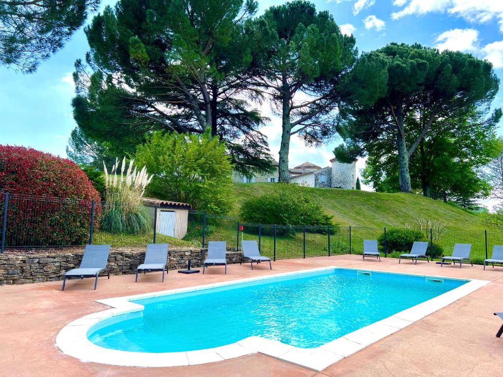 een zwembad met stoelen eromheen met bomen bij Gîtes Château de la Selve in Grospierres