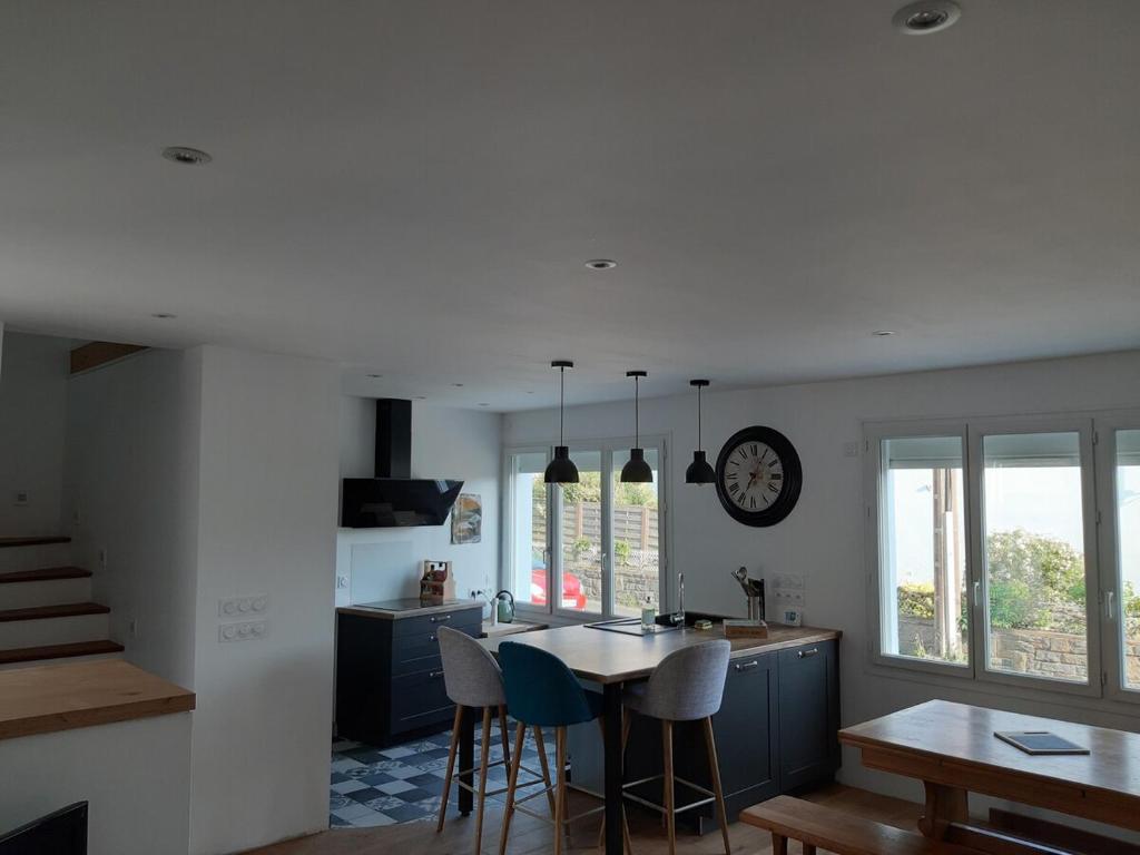 une cuisine avec une table et des chaises et une horloge au mur dans l'établissement Maison de 70 m2 Quartier Manio, à Lorient