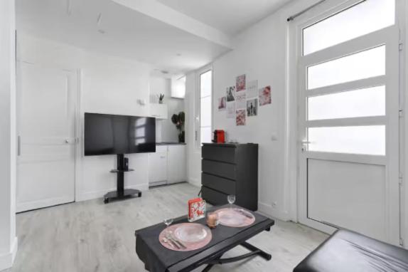 un salon avec une table et une télévision dans l'établissement Fantin Latour studio confortable 2P Seine et tour Eiffel, à Paris