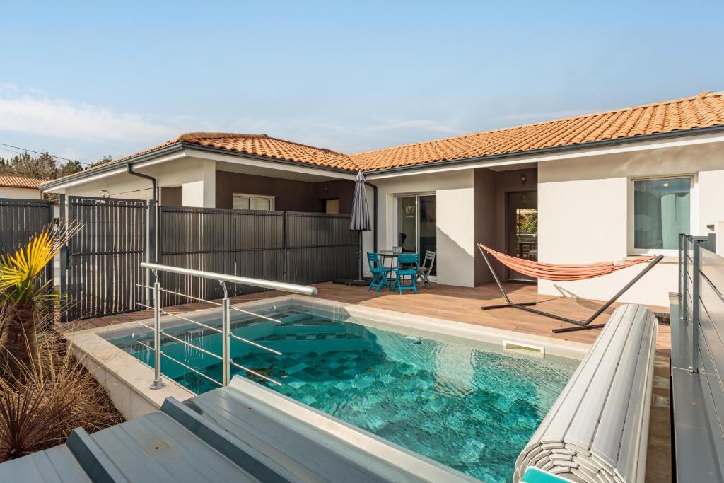 a swimming pool with a hammock and a house at Villa Kaino 2 - Climatisée avec piscine in Ondres