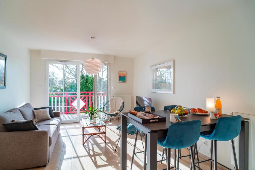 un salon avec une table et des chaises bleues dans l'établissement La Cale de Beg Meil - 100m de la plage, à Fouesnant