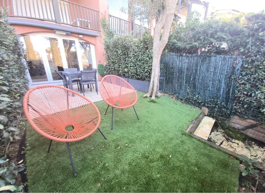 - deux chaises orange et une table dans la cour dans l'établissement GASBRU - Golfe de St-Tropez - Rez de jardin T2 cabine avec accès plage piscine et tennis, à Gassin
