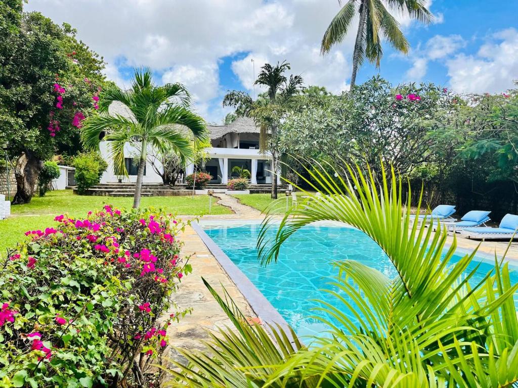 a swimming pool in front of a house with flowers at WHITE Nyumba Malindi in Malindi