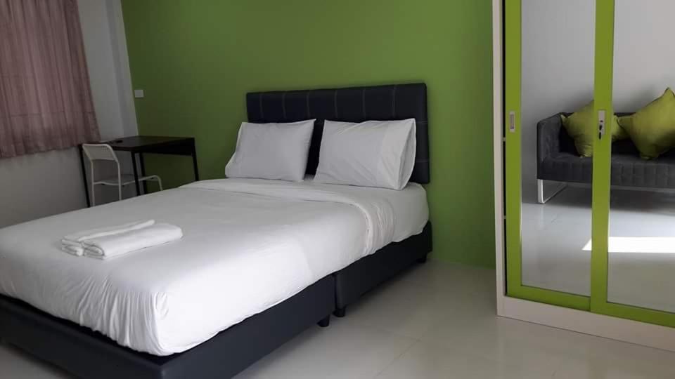a bedroom with a bed and a green wall at The Clover Lampang in Lampang